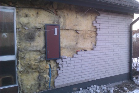 Teglet faller! Det behövs inte speciellt stor hammare för att slå loss stenarna. Några slag så lossnar de. Bara å välta ner sen. Stenarna ligger staplade på varandra med lite bruk emellan. Nästan som kallmurat. Fusk! Notera svartmöglet i isoleringen.